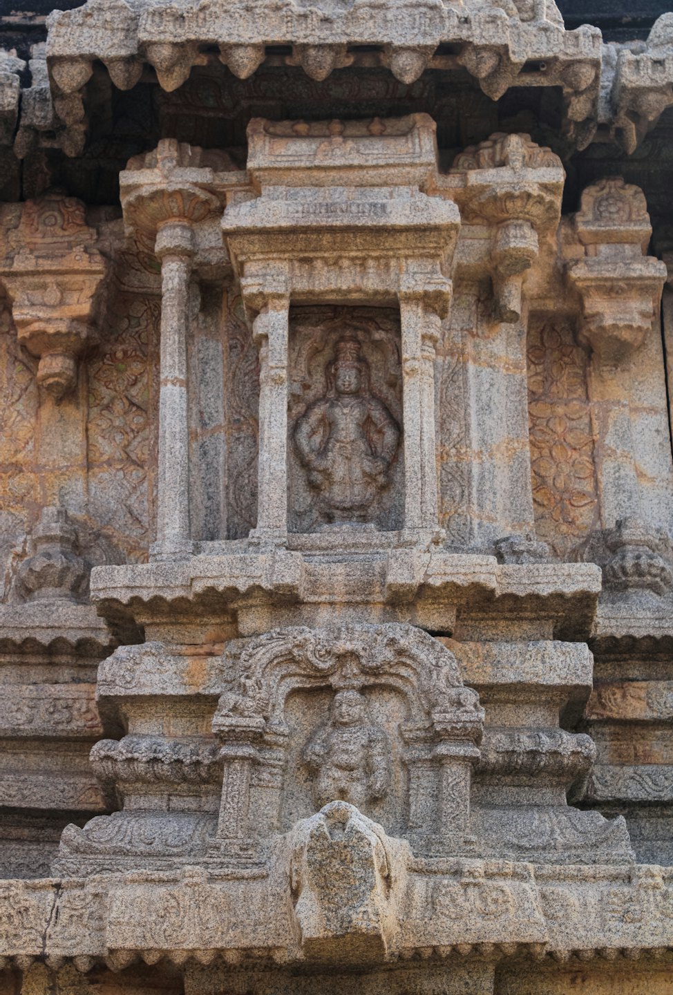 Intricate stone carvings of a deity and seated figure on a temple.