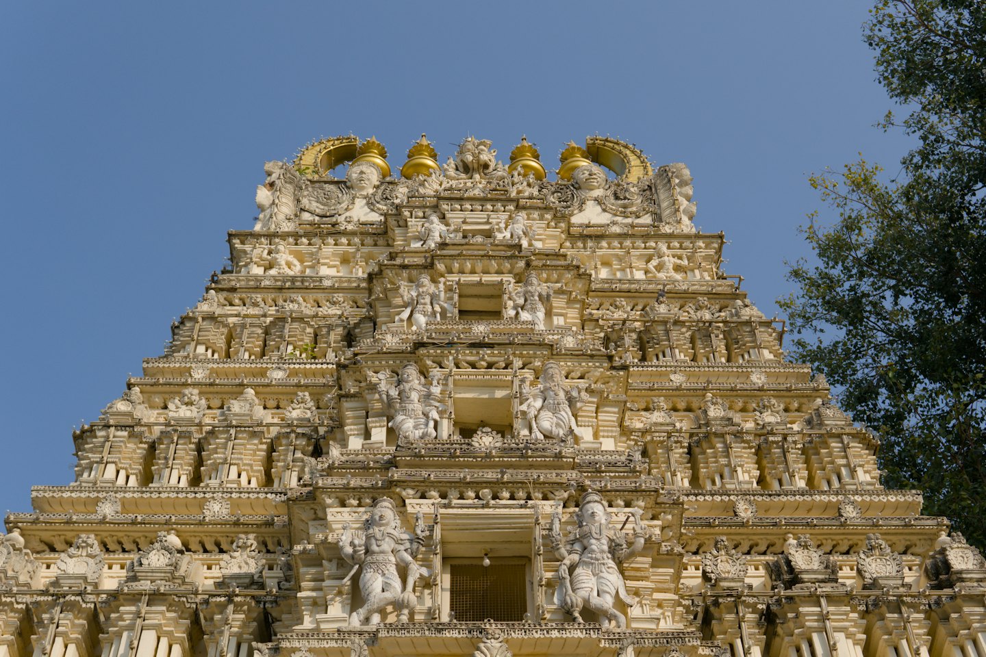 Intricately carved stone Hindu temple tower against a blue sky.