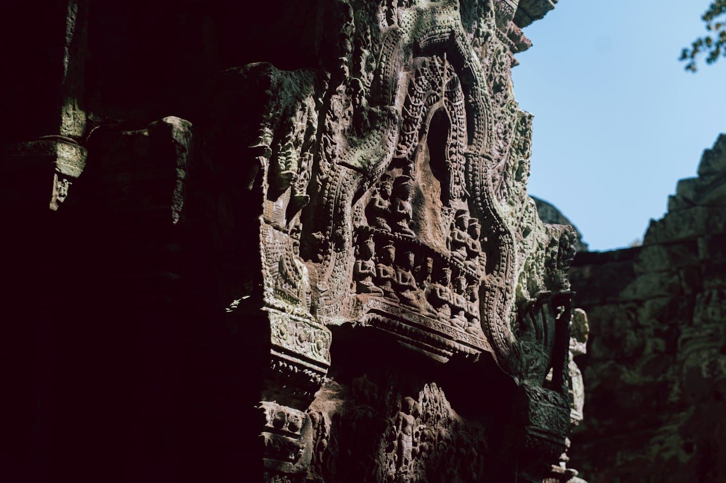 Intricate relief carvings adorn a weathered ancient stone temple wall.