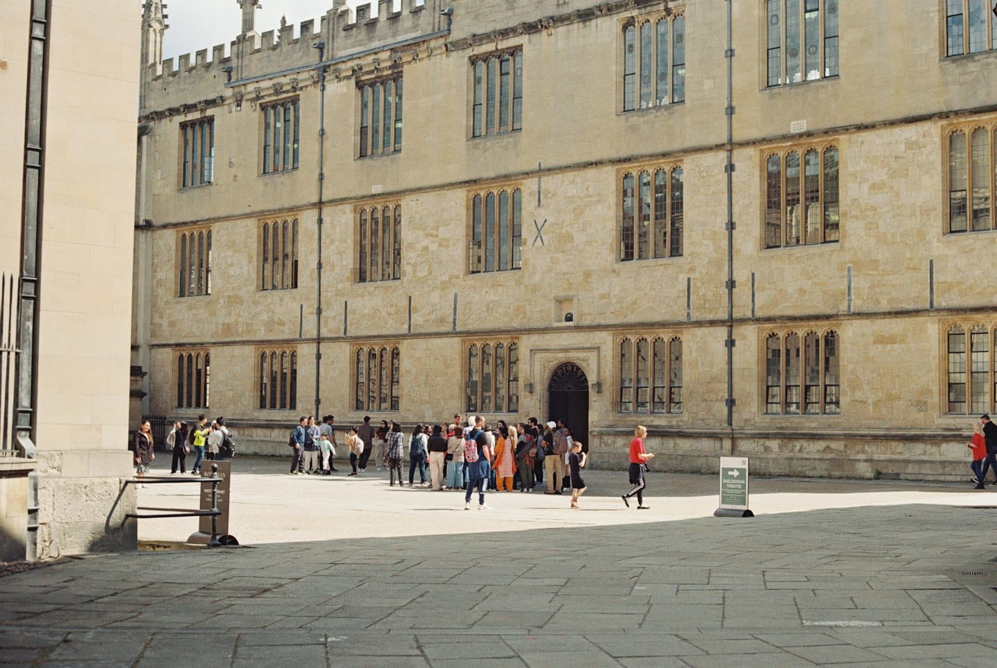 Students walk across a stone courtyard before a historic building.