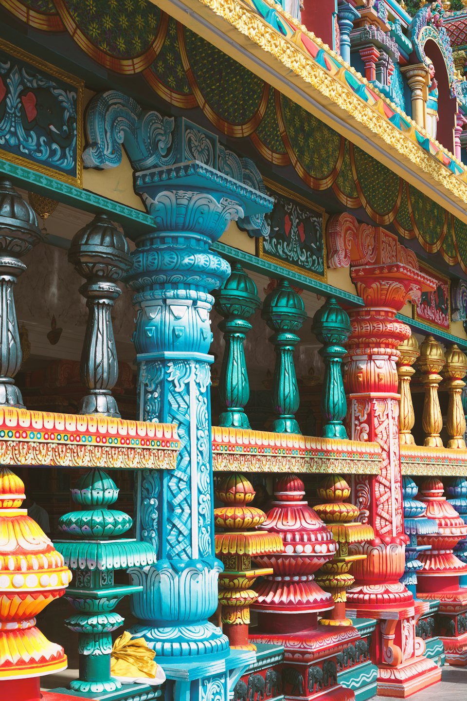 Intricately carved pillars and balusters of a colorful temple exterior.