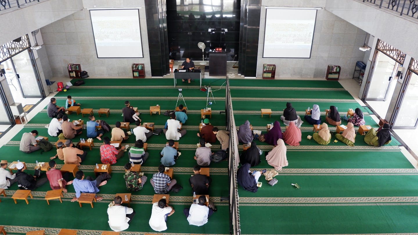 People listen to a speaker presenting in a large hall.